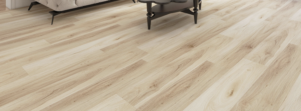 Close-up of light-colored wooden flooring in a living room with a gray sofa and a black coffee table.