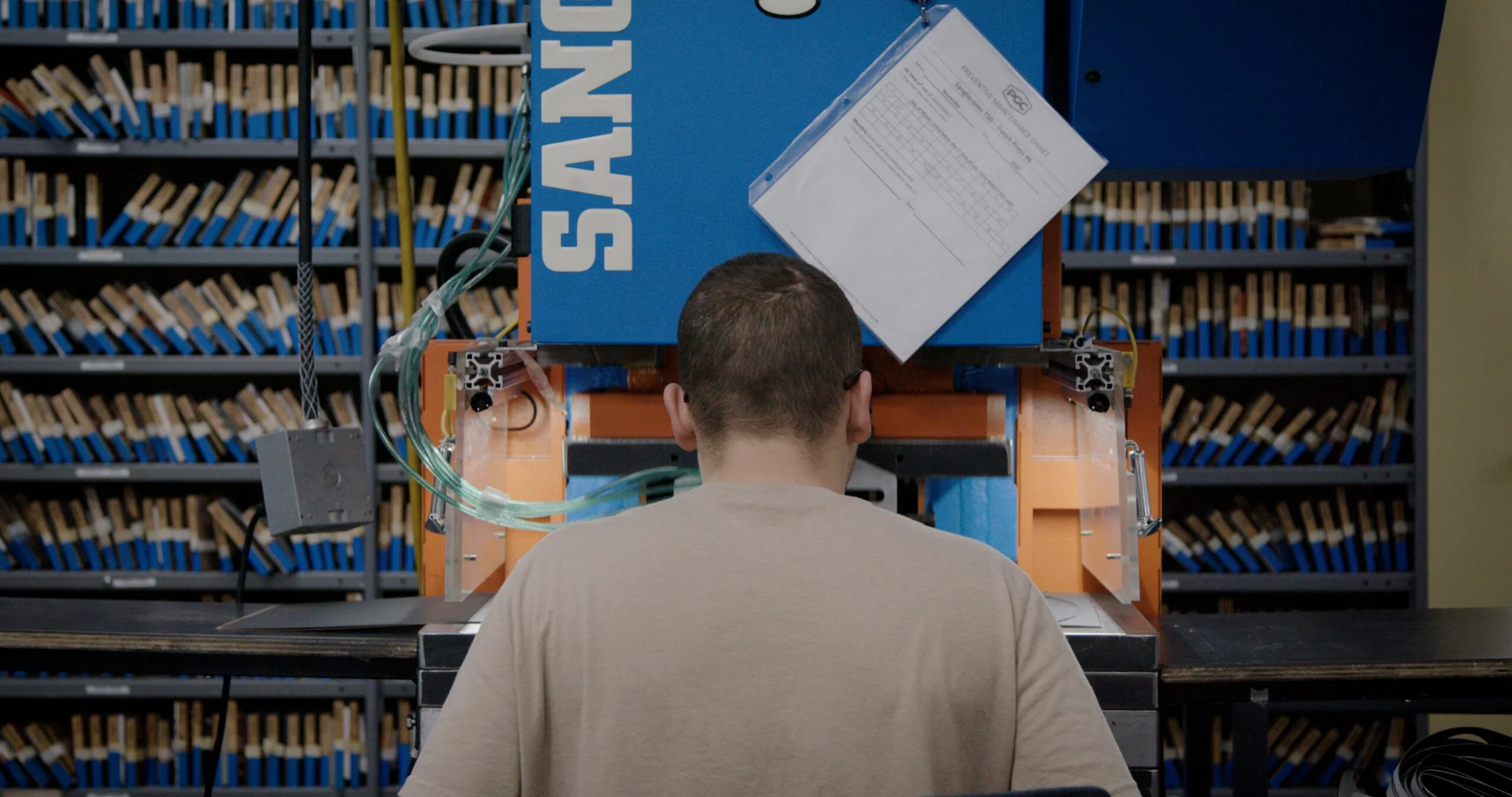 Production still, someone using old school die cutting machine