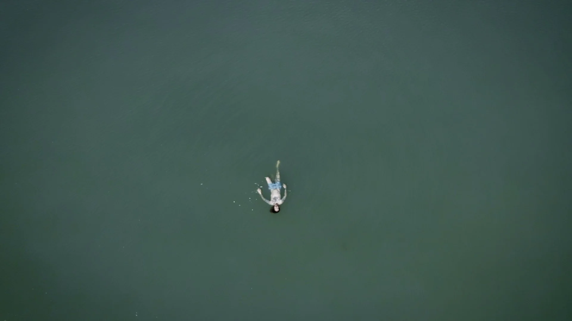 Production still of Jonny Coffman floating in a lake, wide shot