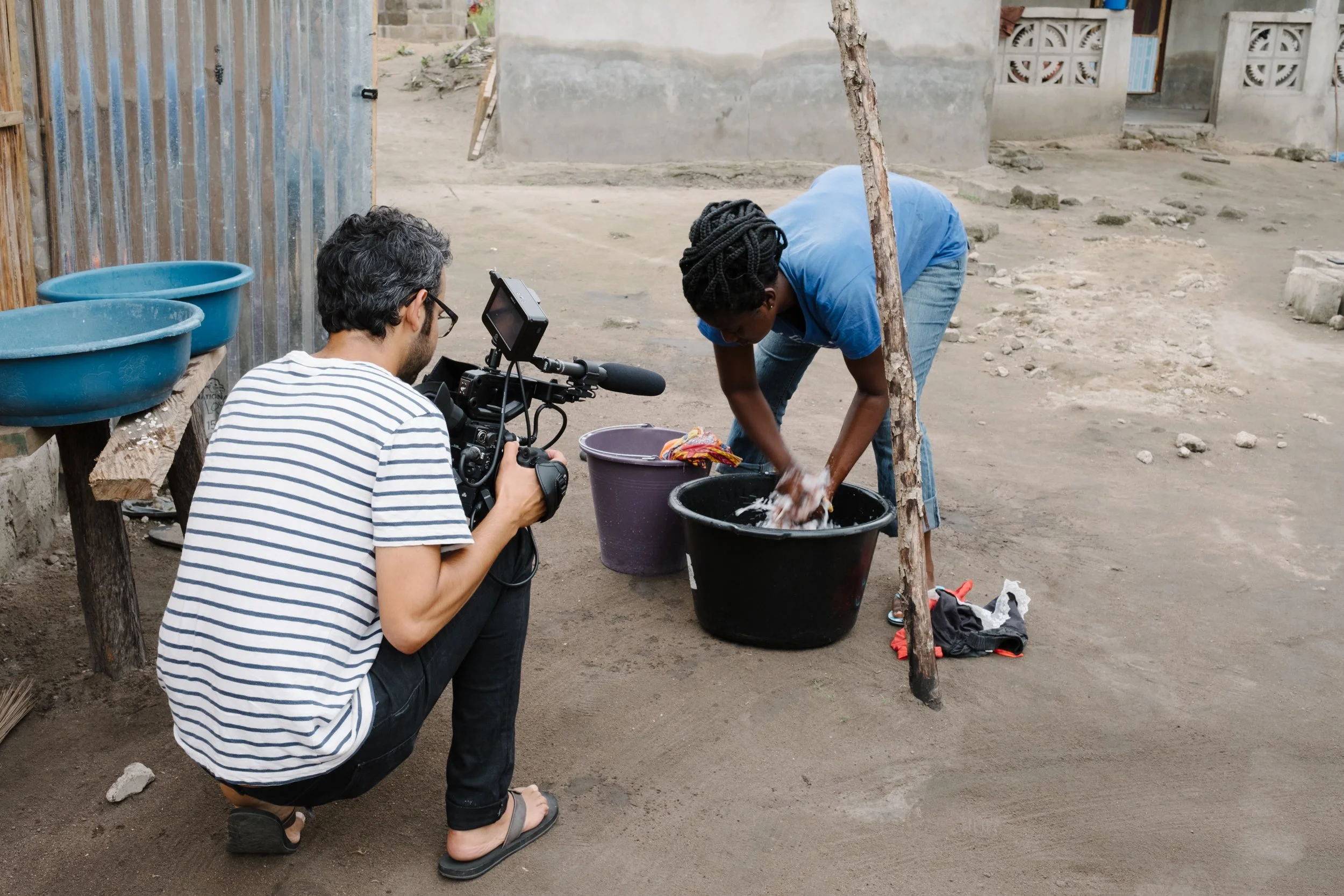 Behind the scenes, cinematographer filming Ghanaian woman washing her clothes in buckets