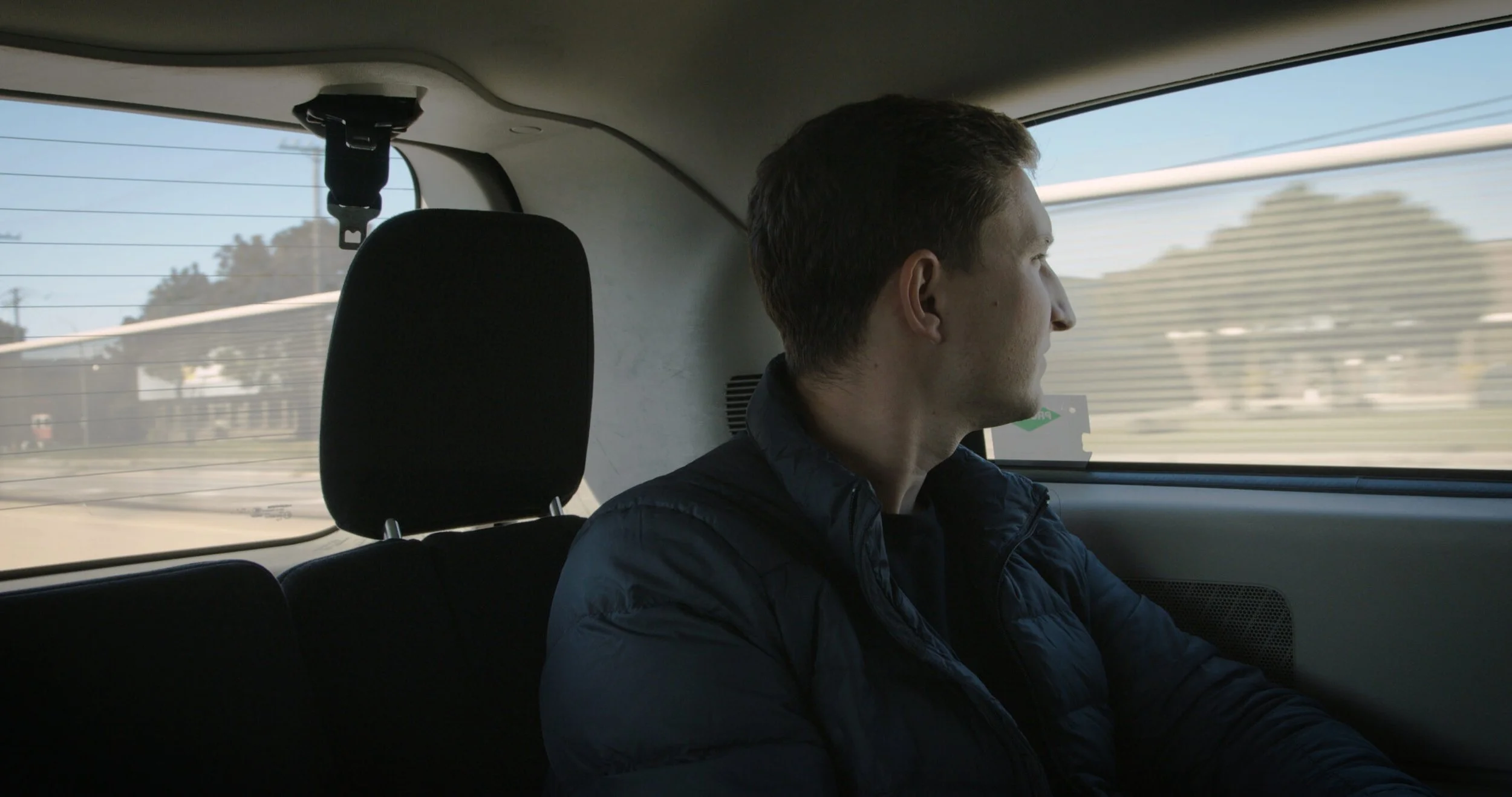 Man in back of a car, pensively looking out the window