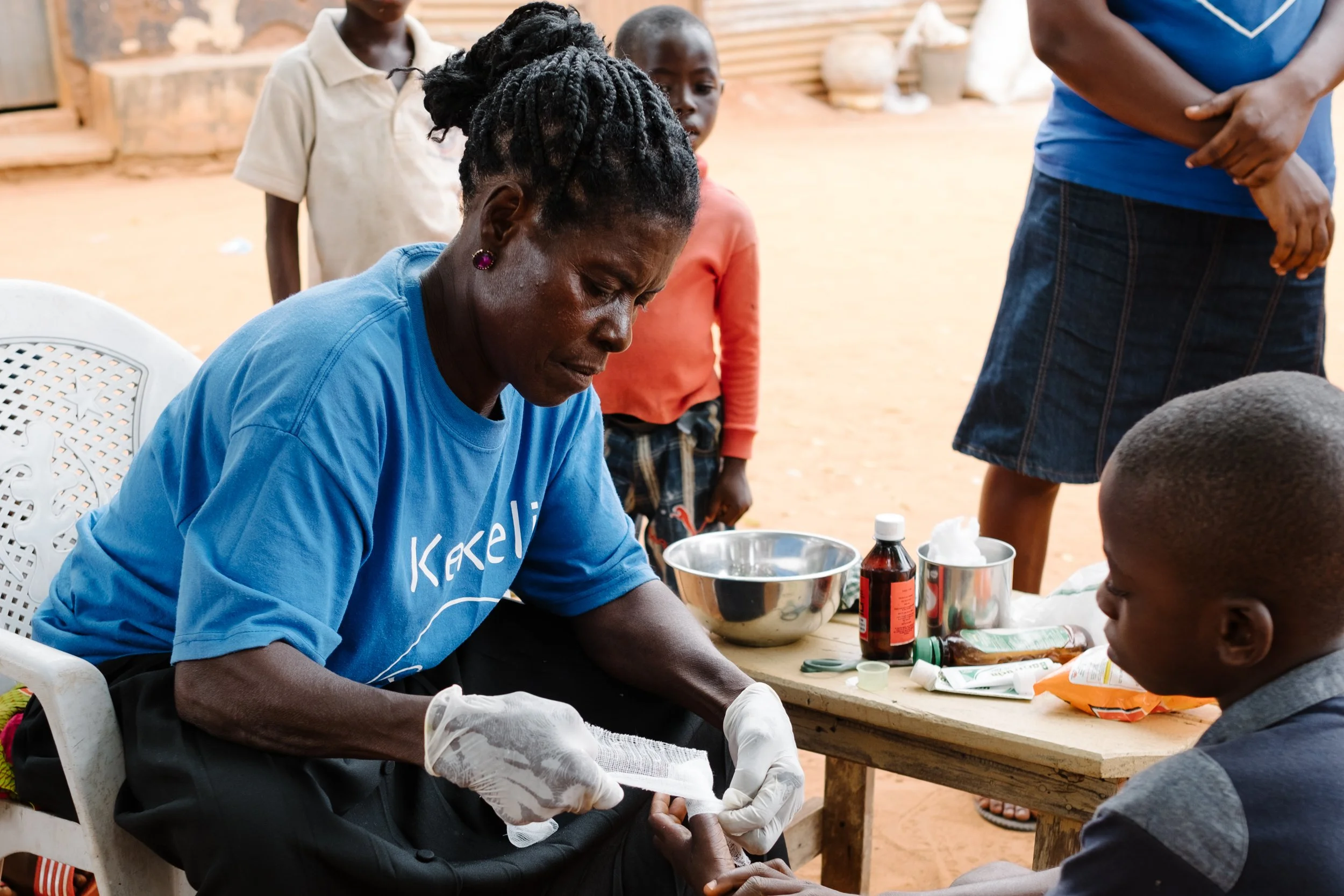 Community health promoter bandaging up a cut on someone's hand