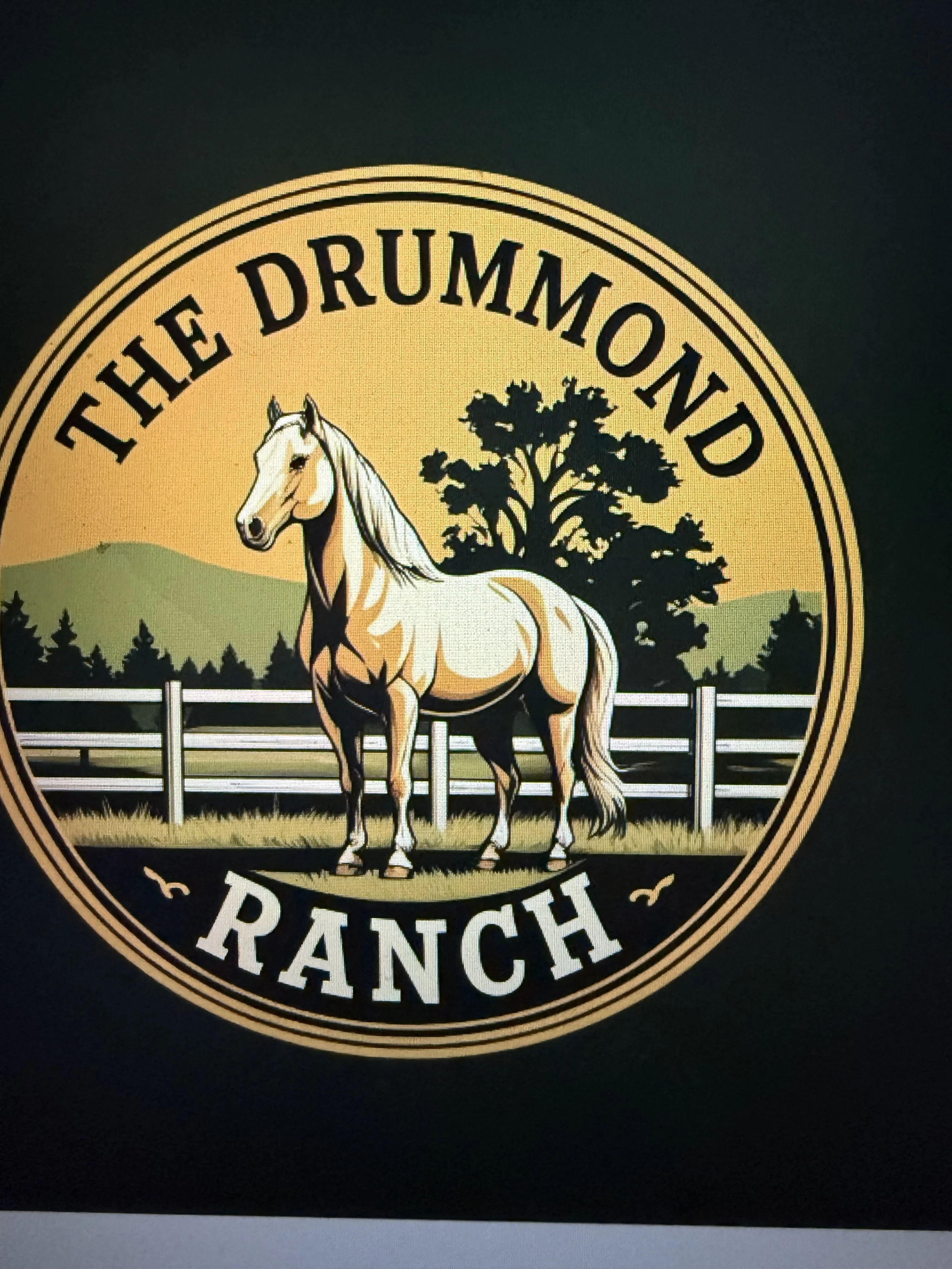 Logo of The Drummond Ranch featuring a white horse with a flowing mane standing in front of a wooden fence, with trees and hills in the background.