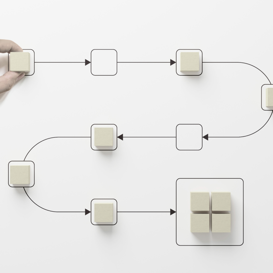 Diagram with interconnected white square blocks and a hand placing one on a white surface, illustrating a flow or process.