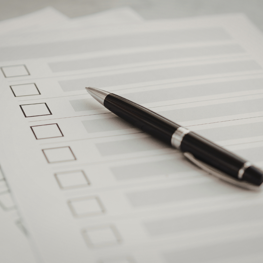 A black pen resting on a printed checklist or survey form with multiple empty checkboxes.