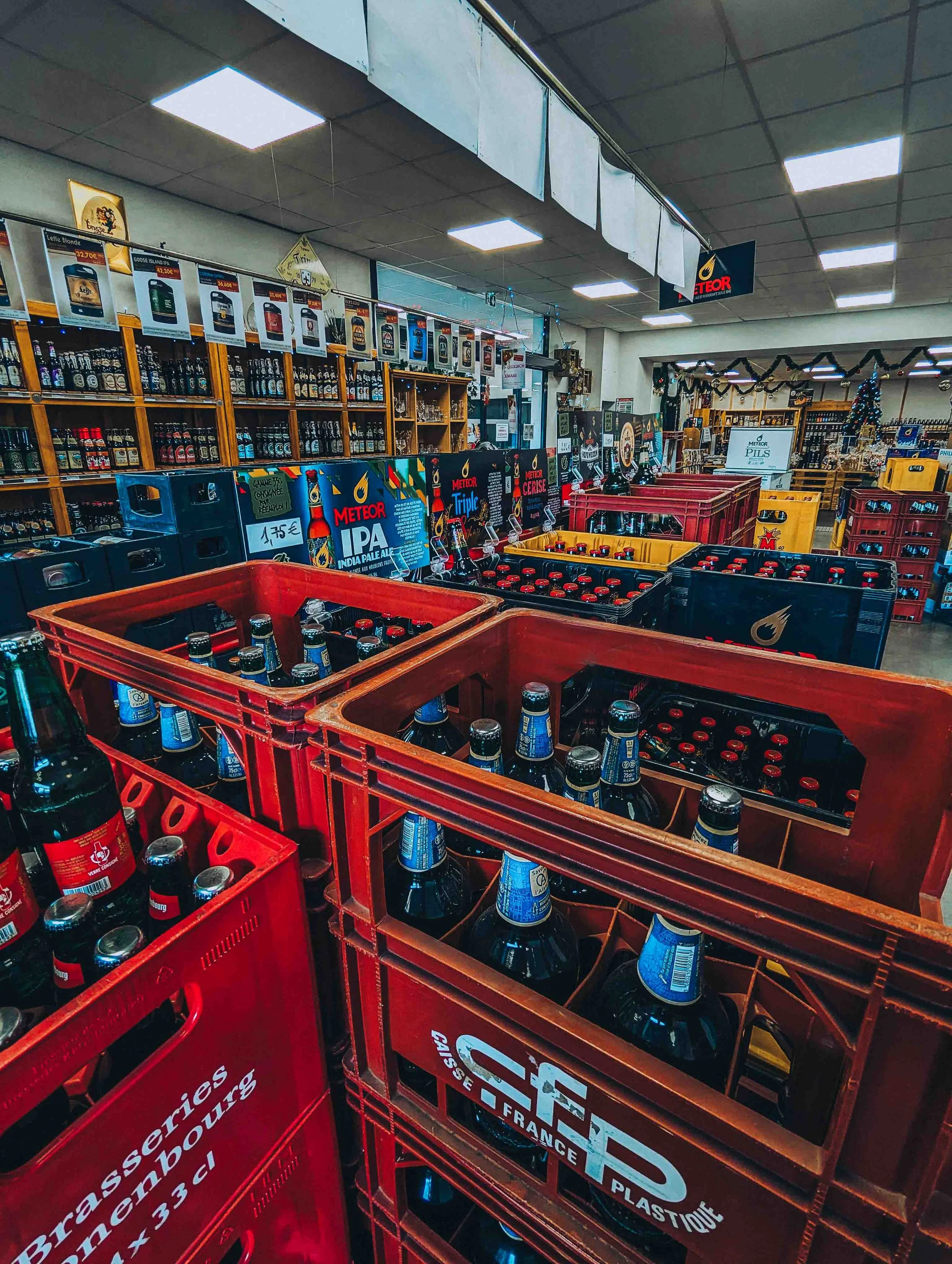 Rayons de magasins avec des caisses de boissons consignées ; eaux, bières, jus et soft