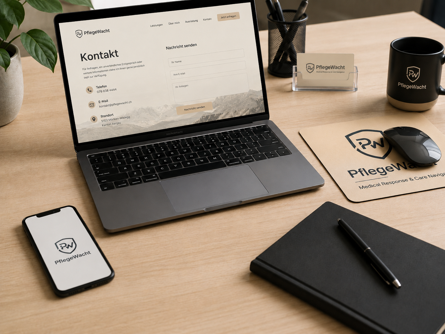 Arbeitsplatz mit Laptop, Smartphone, Notizbuch, Stift, Tasse, Visitenkartenhalter, und Maus auf Mousepad, alle Marken mit PflegeWacht Logo.