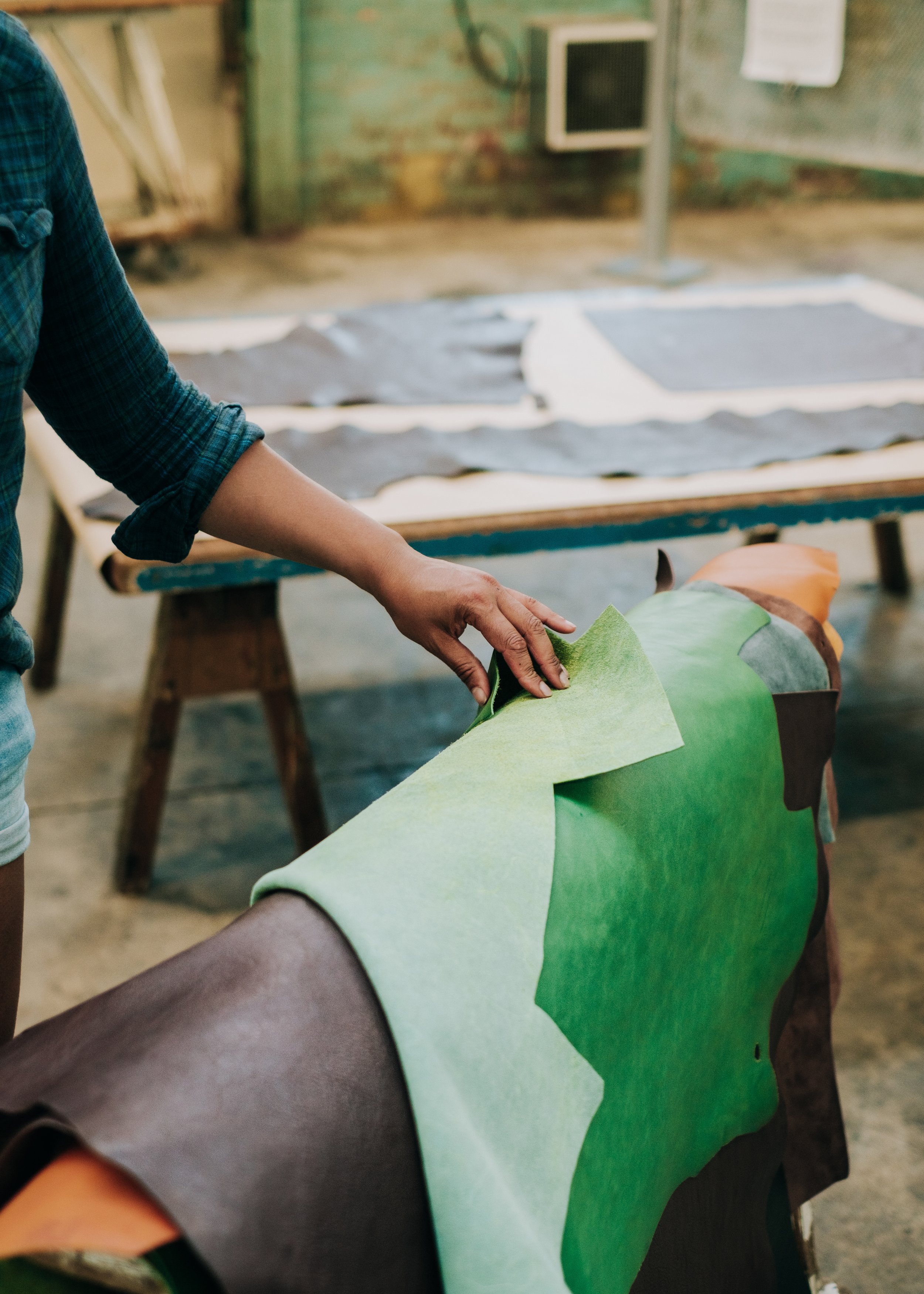 Person wrapping a colourful leather on someone's arm, with a workshop or art studio setting in the background.