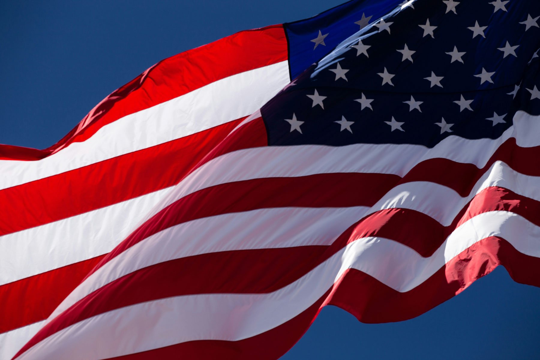 American flag waving against a blue sky.