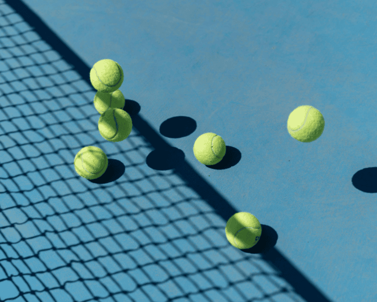 Zes tennisballen op een blauwe tennisbaan, met schaduwen en een net.