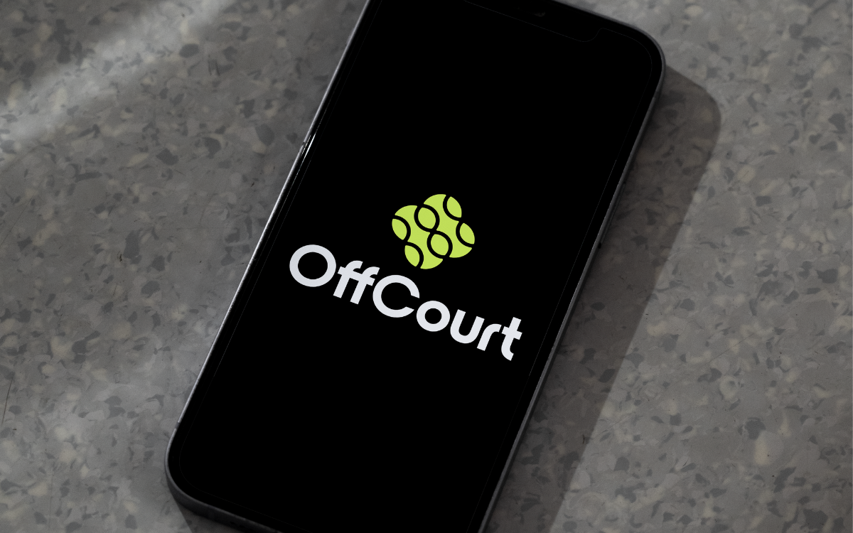 Een smartphone met het Offcourt logo op het scherm, geplaatst op een grijze spekstenen oppervlak.