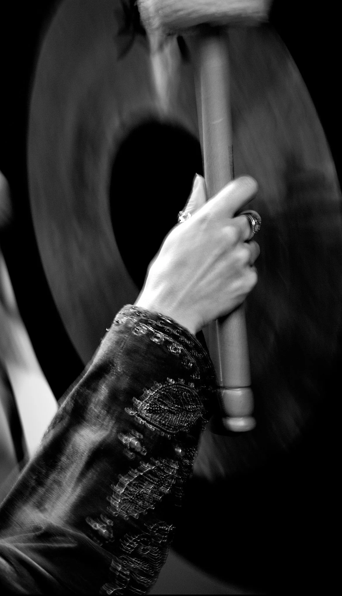 A person's hand holding a gavel in front of a judge's bench, with wood paneling in the background.