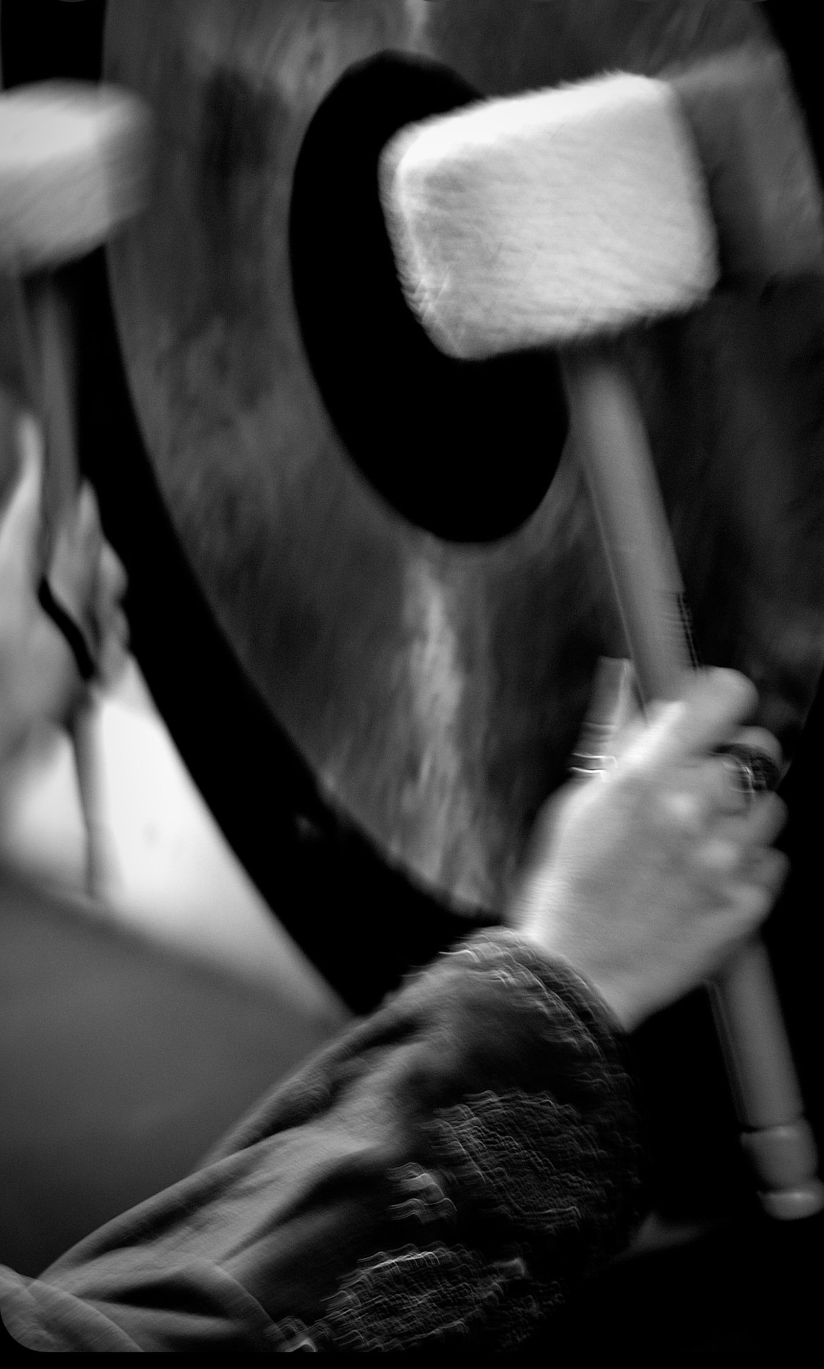 A person playing the gong up closein a black and white photograph.