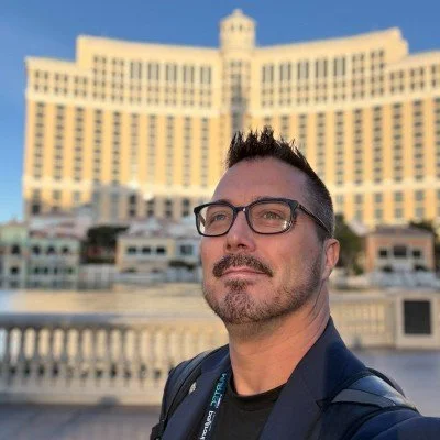 A man with glasses and a beard taking a selfie in front of the Atlantis Paradise Island hotel in the Bahamas.