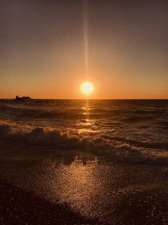 Sunset over the ocean with waves crashing onto the beach. From Dr. Michael Kellis's village in Greece.