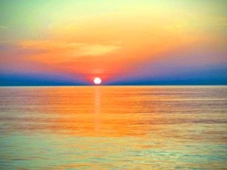Sunset over a calm ocean with colorful sky and reflections on the water. From Dr. Michael Kellis's village in Greece.