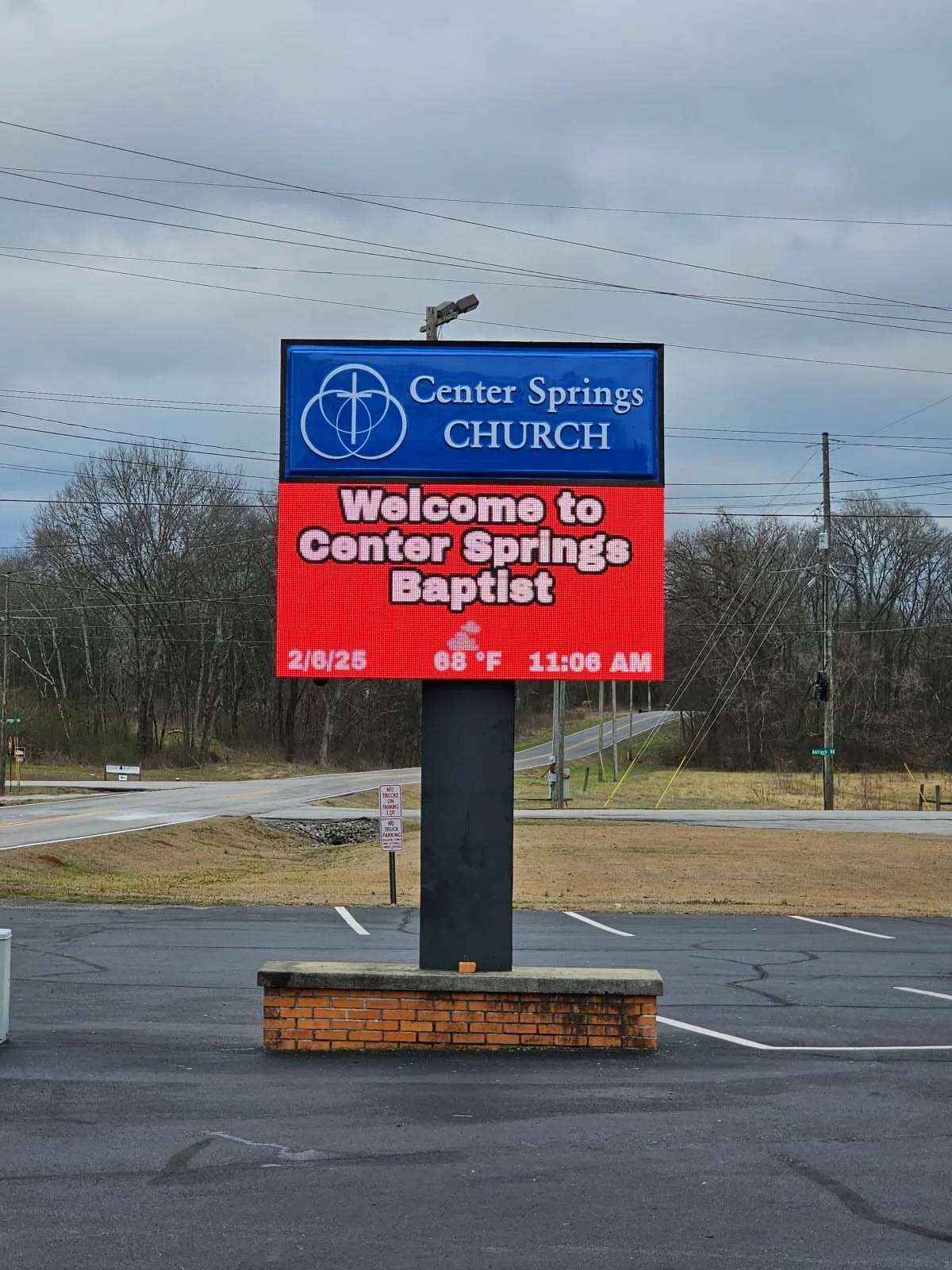 Digital sign in a parking lot displaying information for Center Springs Church, welcoming visitors to Center Springs Baptist, with the date, temperature, and time.