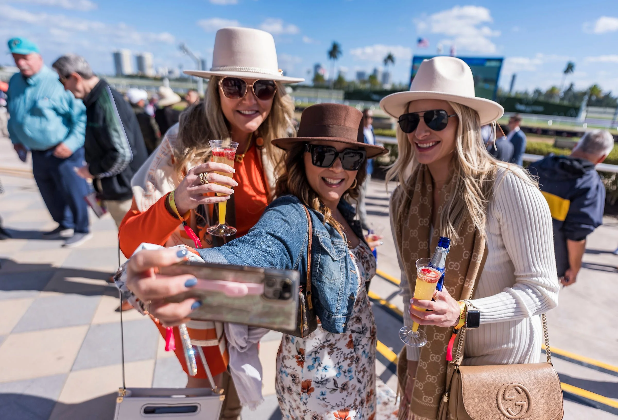 Group of racehorse owners enjoying drinks and taking a selfie at the racetrack, showing the social side of ownership