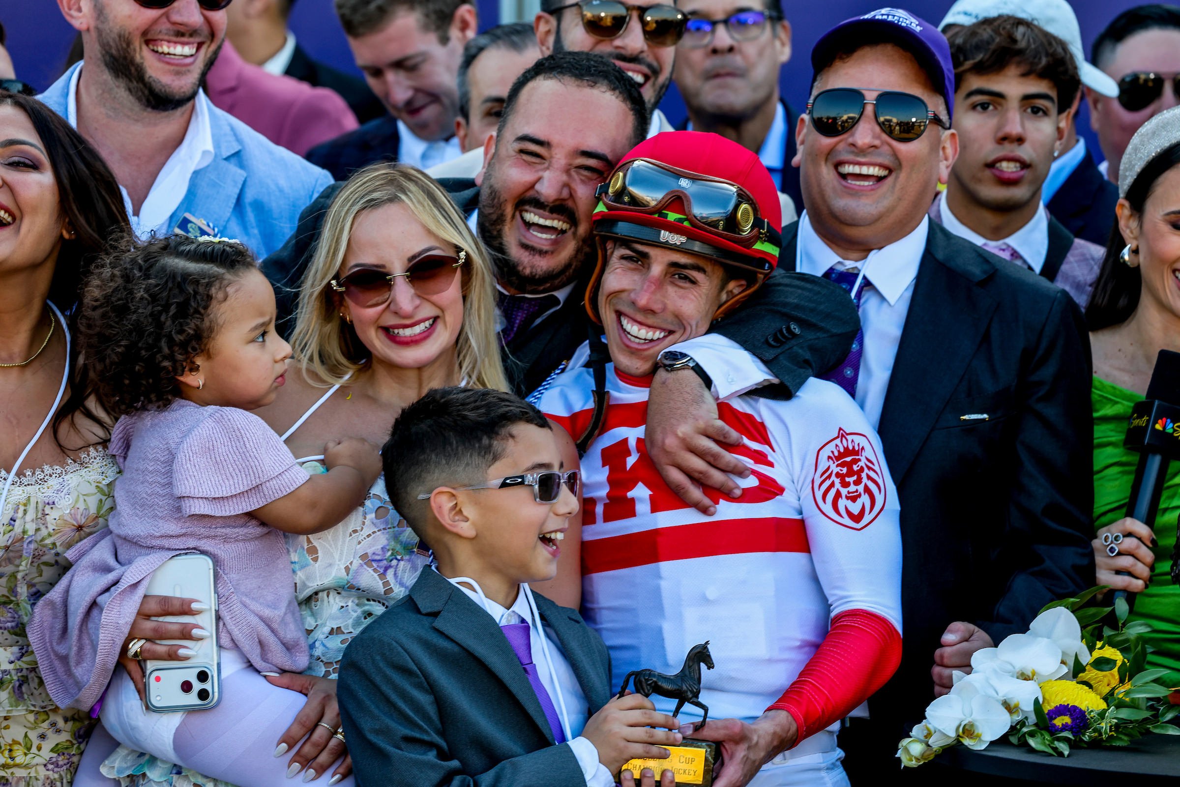 Group of racehorse owners celebrating with a jockey after a race, representing the excitement of finding your path into ownership