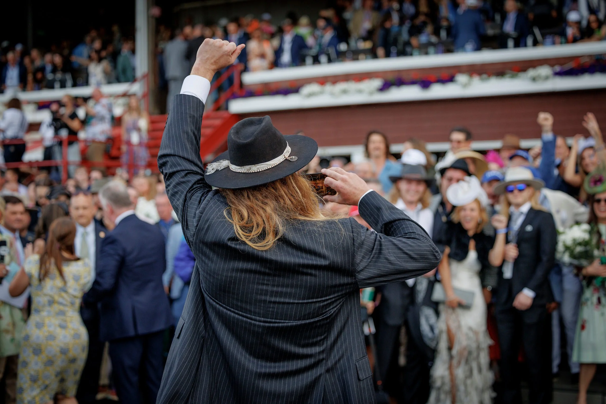 Owner celebrating with a crowd at Saratoga racetrack during a racehorse syndicate win