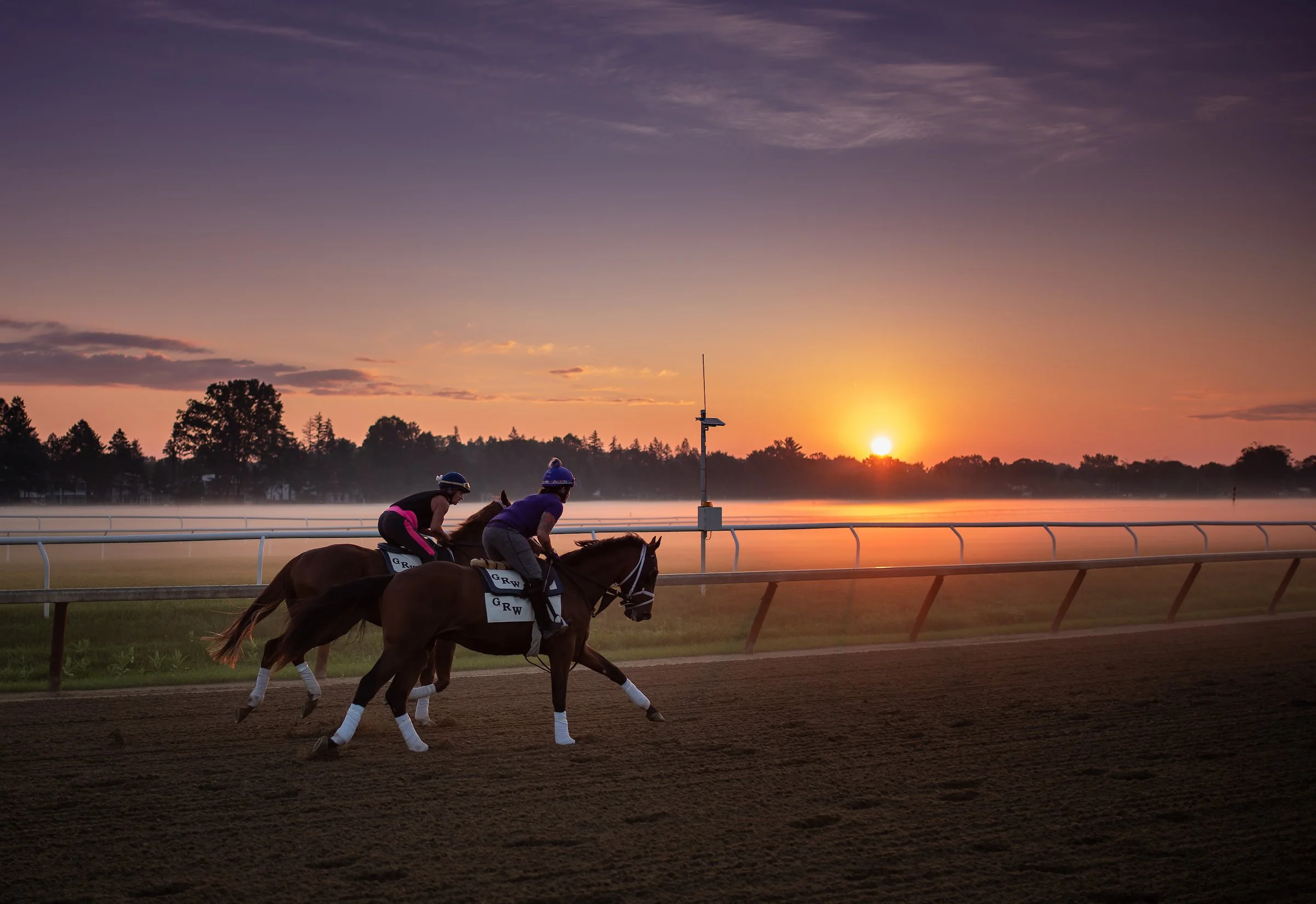 Racehorses training at sunrise on the track, showing the daily commitment and routine of full ownership
