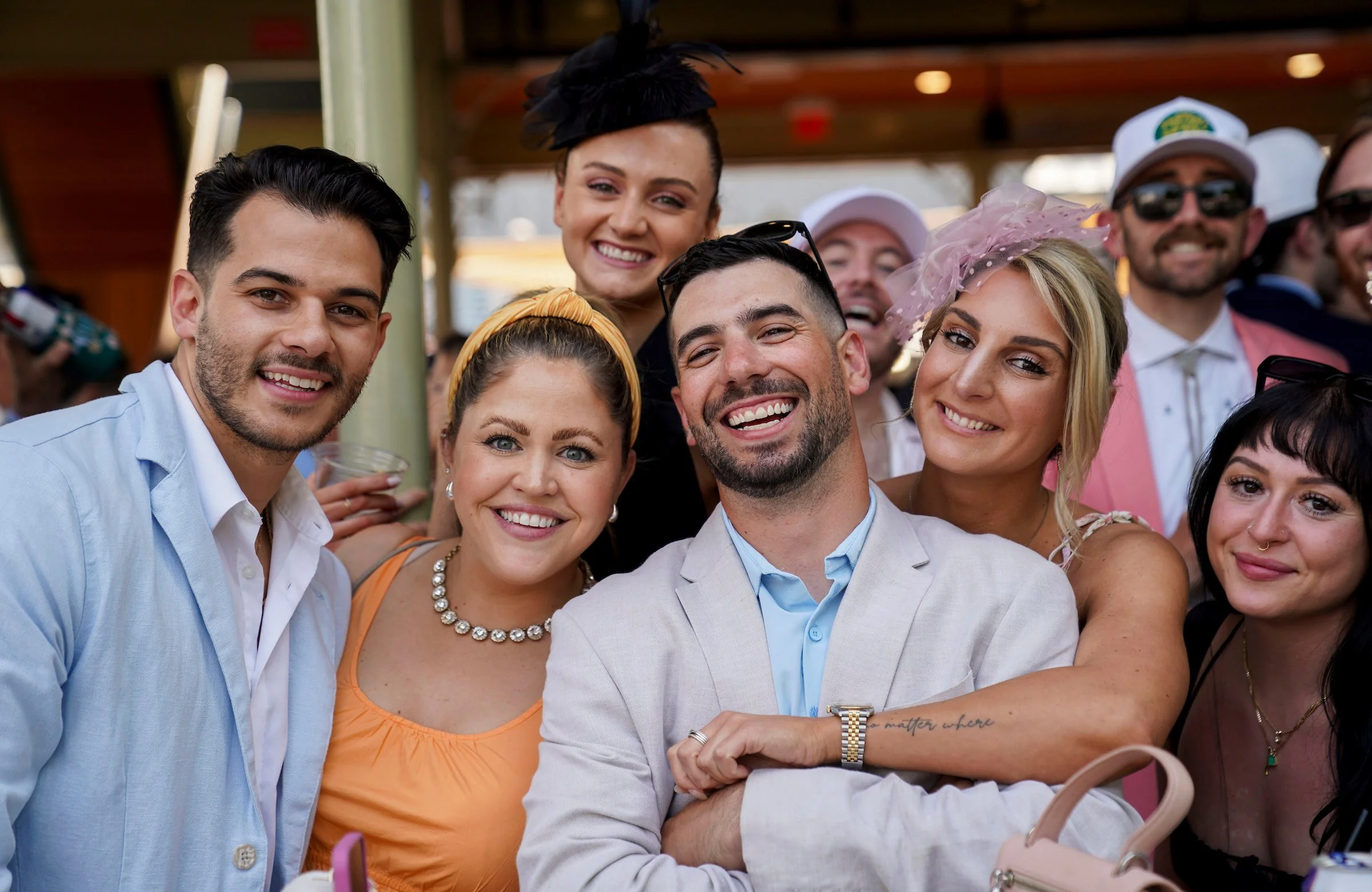 Group of racehorse owners smiling together at the racetrack, representing the community-focused approach of America’s Best Racing