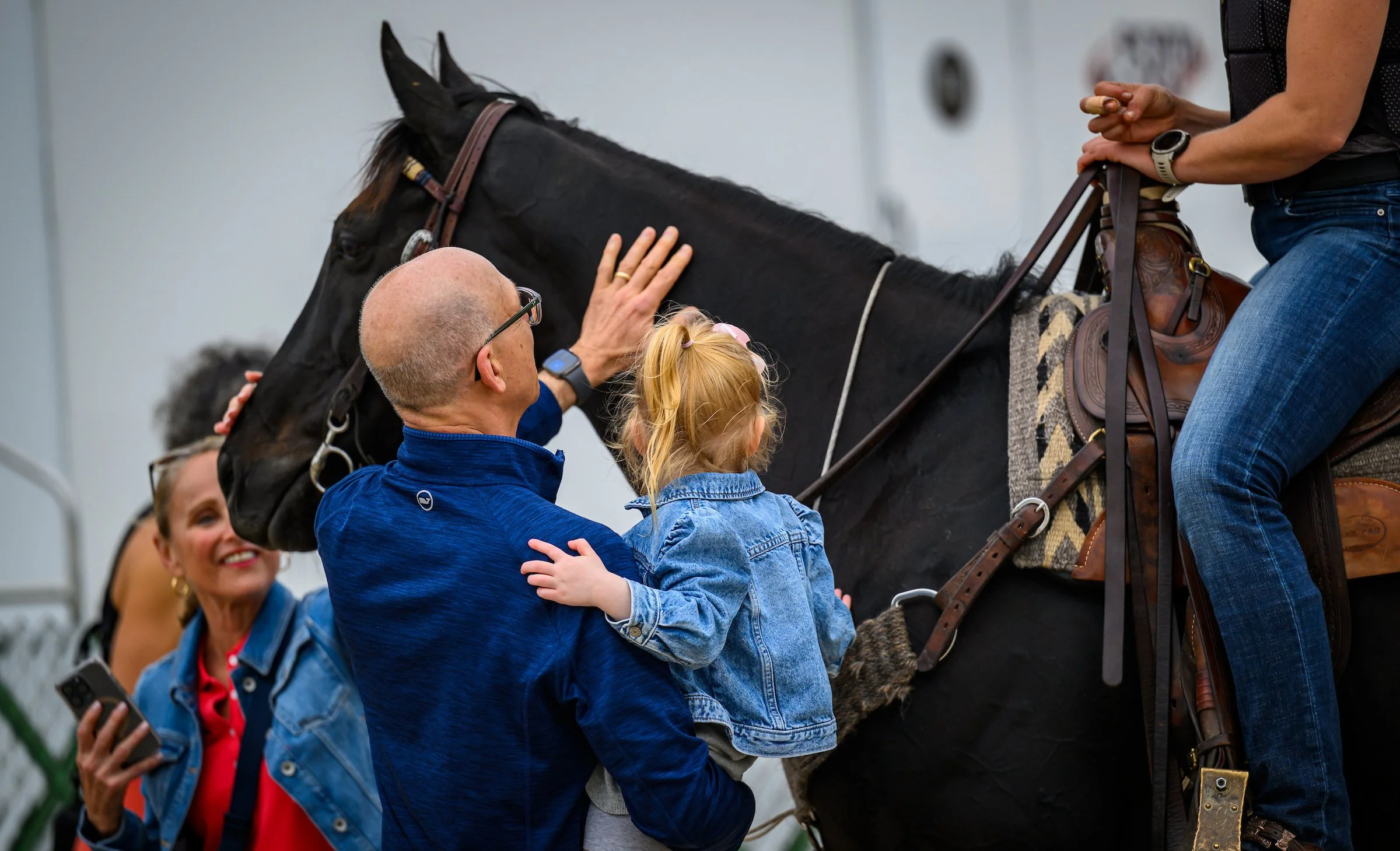 Adult and child interacting with a racehorse, representing the personal and accessible experience of racehorse ownership