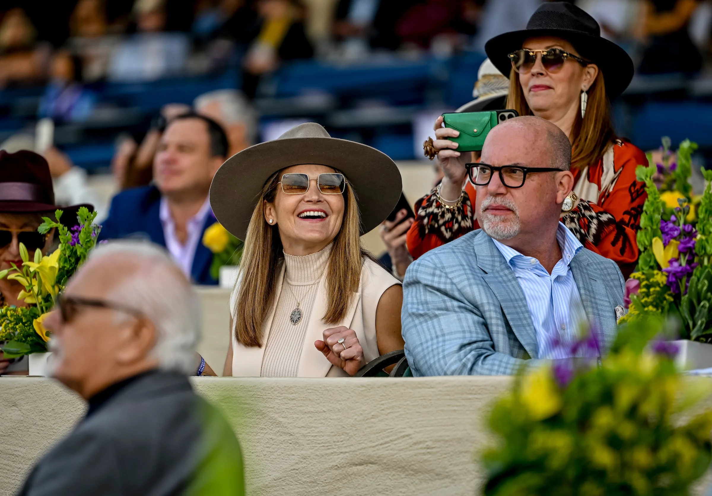 Racehorse owners watching a race from premium seating at the racetrack, reflecting the experience of full ownership