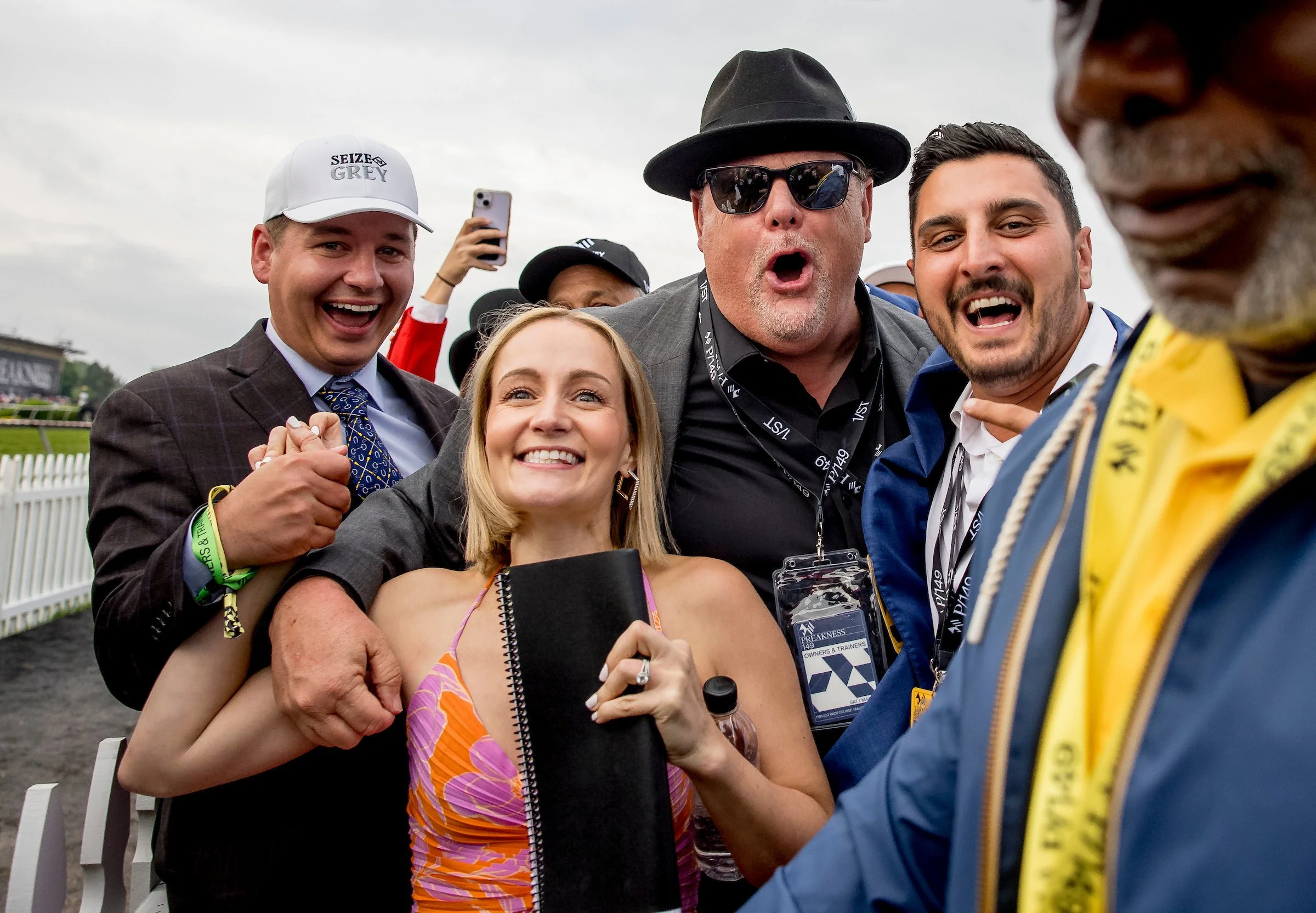 Group of racehorse owners celebrating together at the track, highlighting the excitement of getting involved in ownership