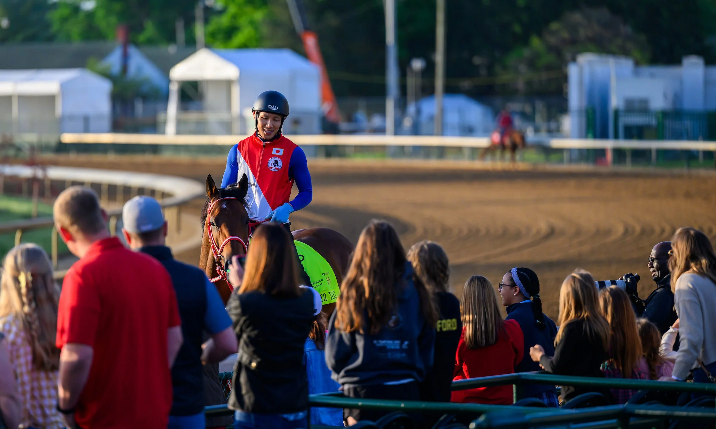 Racehorse and jockey passing by a group at the track, showing the close, trackside experience of racehorse ownership