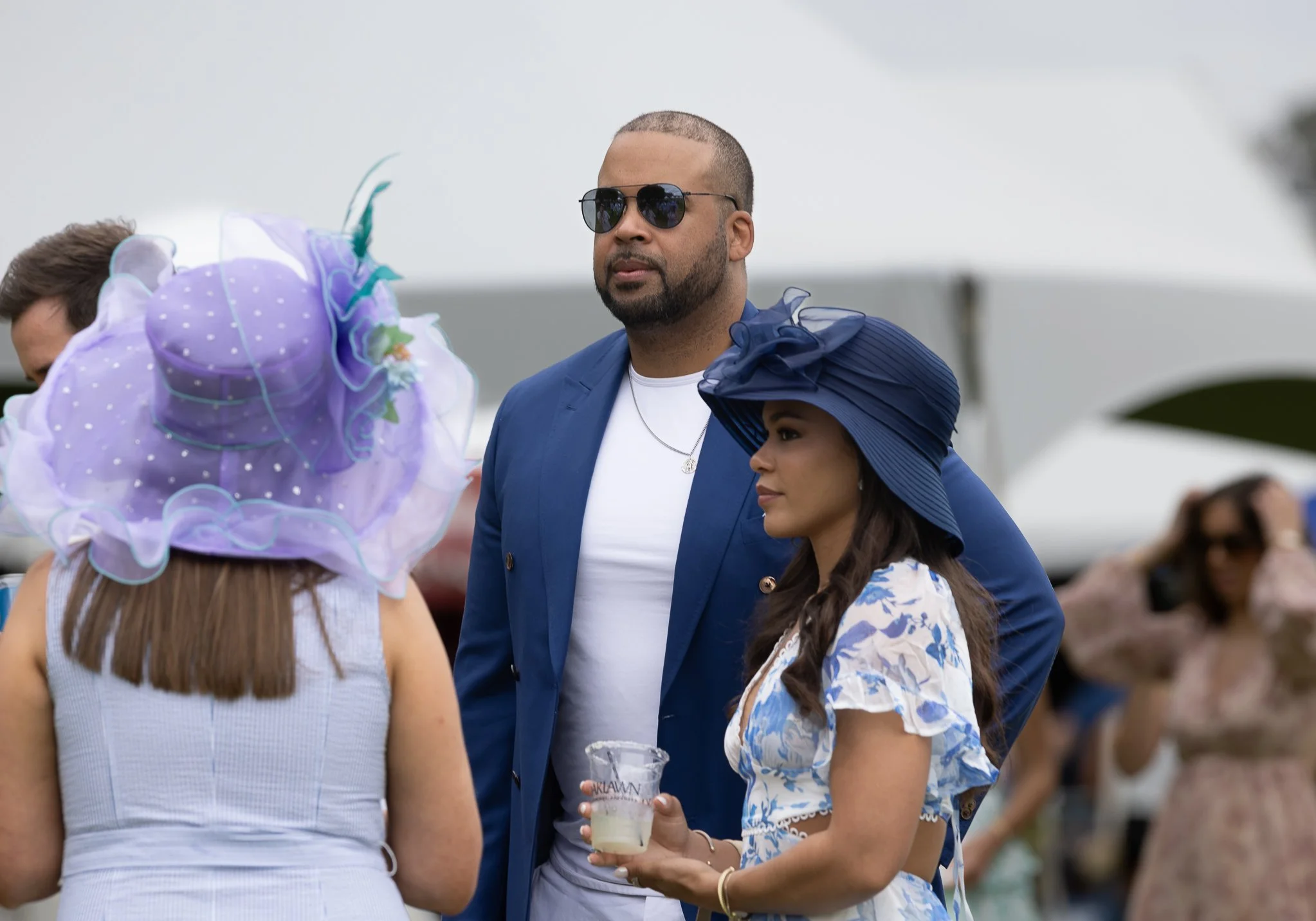 Racehorse owners standing trackside in a crowd, showing the atmosphere and social experience of ownership