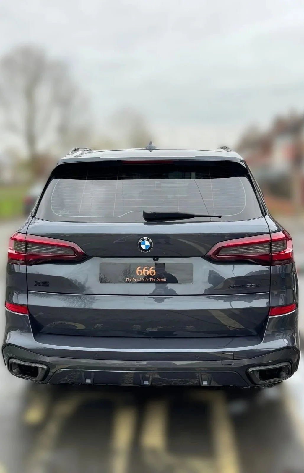 Black BMW X5 SUV parked outdoors with a blurred background, featuring a license plate that reads "666" with the tagline "The Devil is In The Detail."