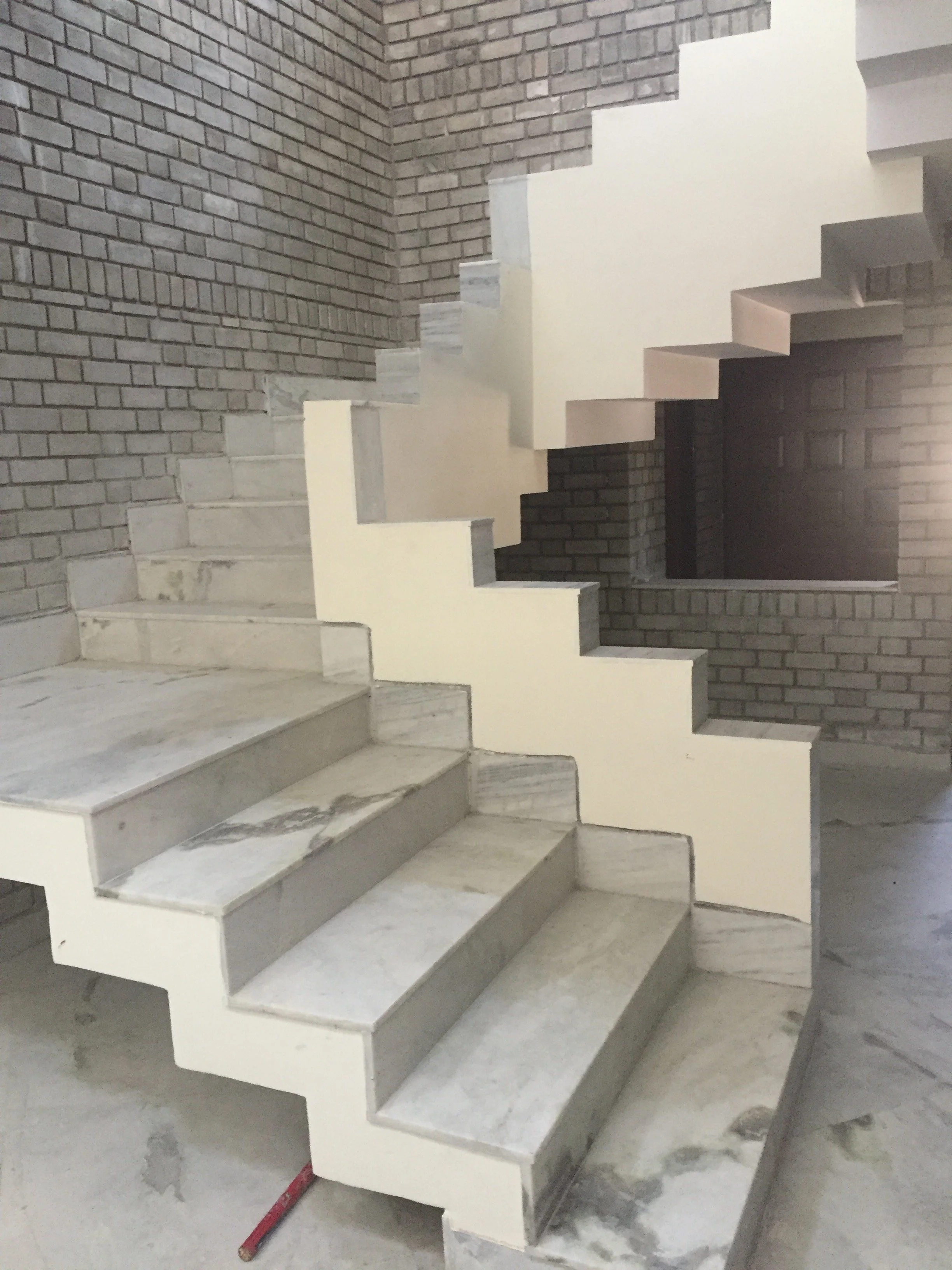 A staircase with marble steps and a brick wall background, under construction or renovation.