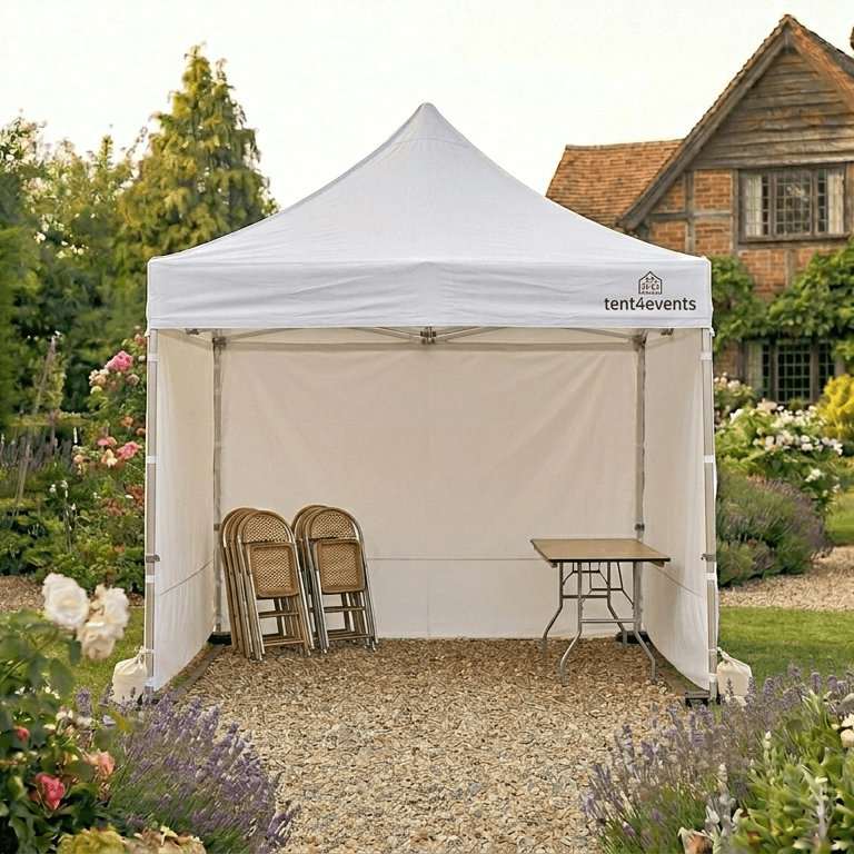 Ein weißer Zeltpavillon mit Stühlen und einem Tisch im Garten eines Hauses mit Blumen und Bäumen.