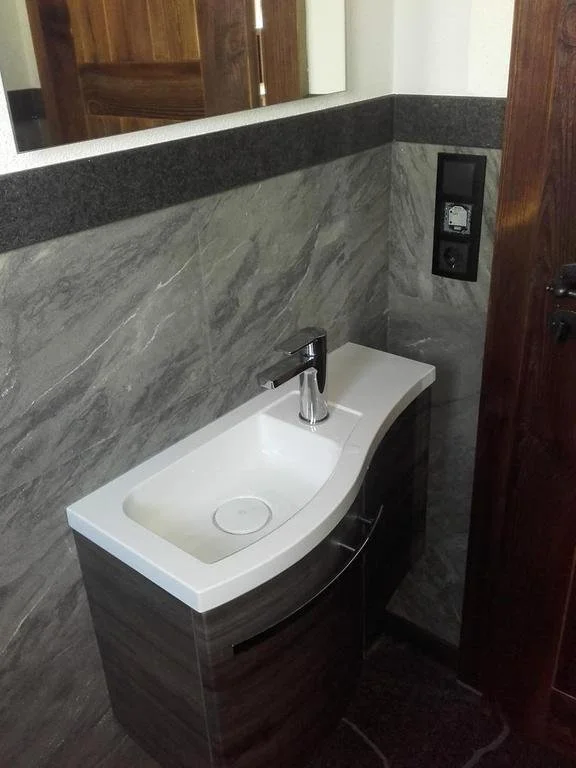 Kleiner Waschtisch mit angebrachtem Wasserhahn in einem Badezimmer mit Steinwänden und Sitzbank