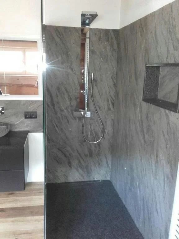 Moderne Dusche mit grauer Marmorwand und Handbrause