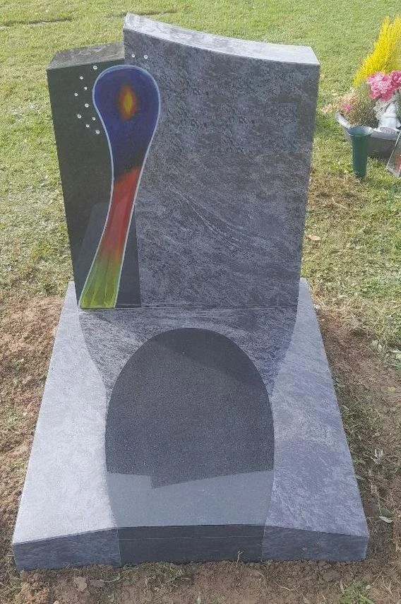 Grabstein mit buntem Regenbogen-Design und schwarzem Bogen auf grauem Untergrund