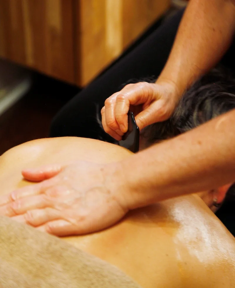 En person som ger en massage på en persons rygg, som ligger ner.