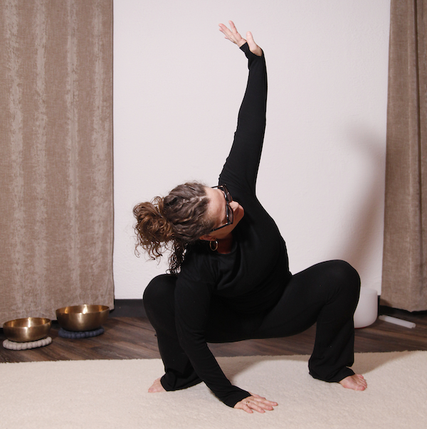 Person som utför en yogaställning på golvet inomhus.