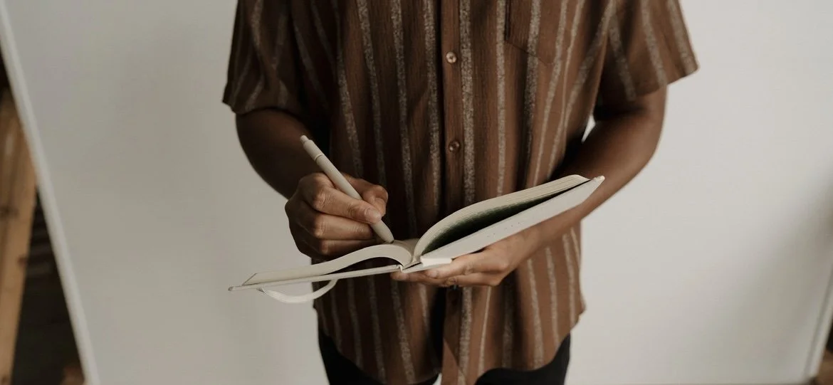 Therapist wearing a brown shirt and writing in a notebook