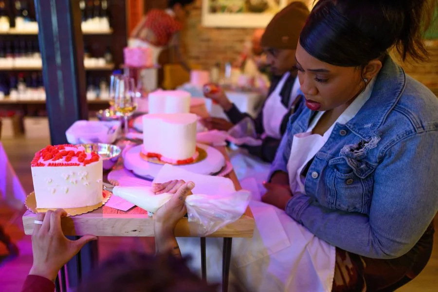 People at a cake decorating workshop, decorating cakes with frosting and toppings.