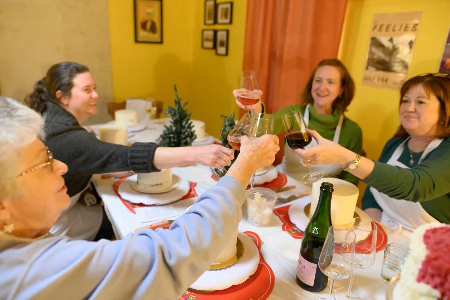 A group of women celebrating at a dinner table, raising glasses of wine in a toast during a festive gathering.