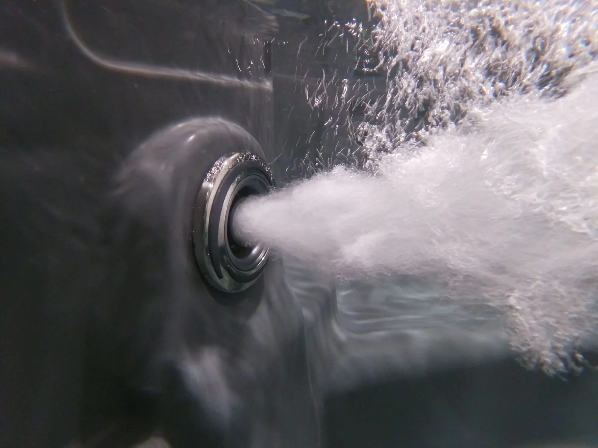 A close-up of a hot tub jet spraying water.