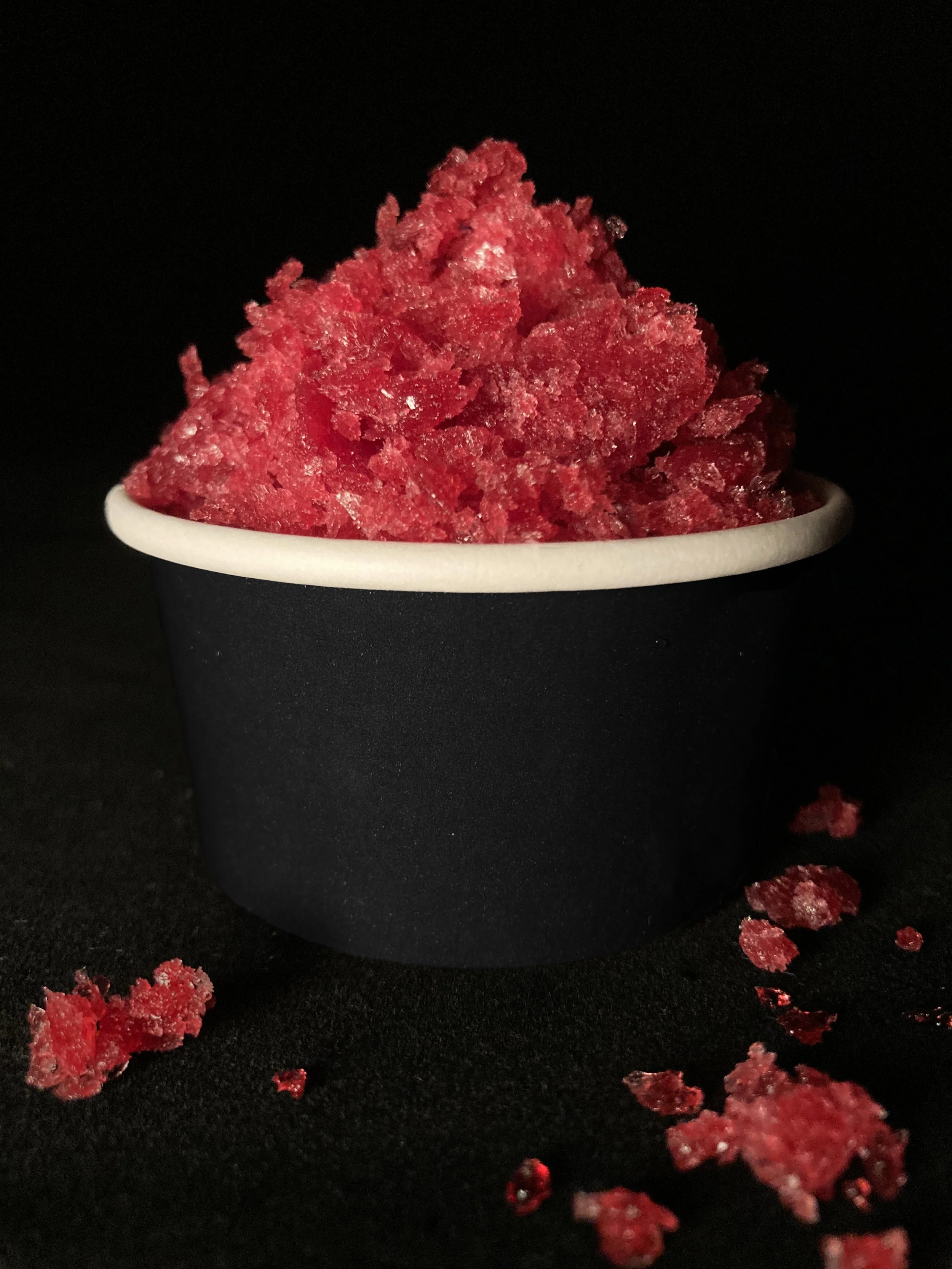 Cup of black currant granita against a black background