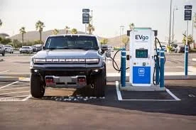 A pickup truck charging at an electric vehicle charging station in a parking lot.