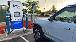 Electric vehicle charging station with a gray electric SUV parked next to it.