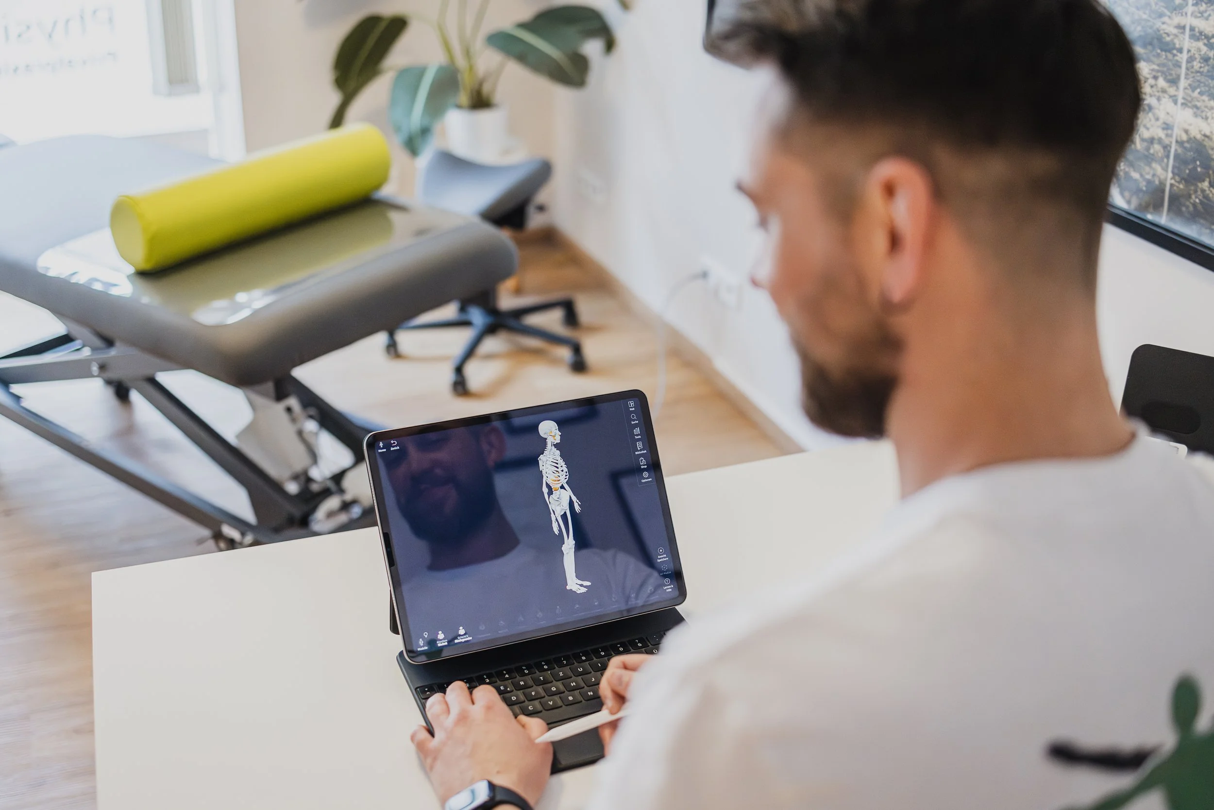 Ein Mann arbeitet an einem Laptop mit einer digitalen Skelett-Animation auf dem Bildschirm in einem modernen Büro.