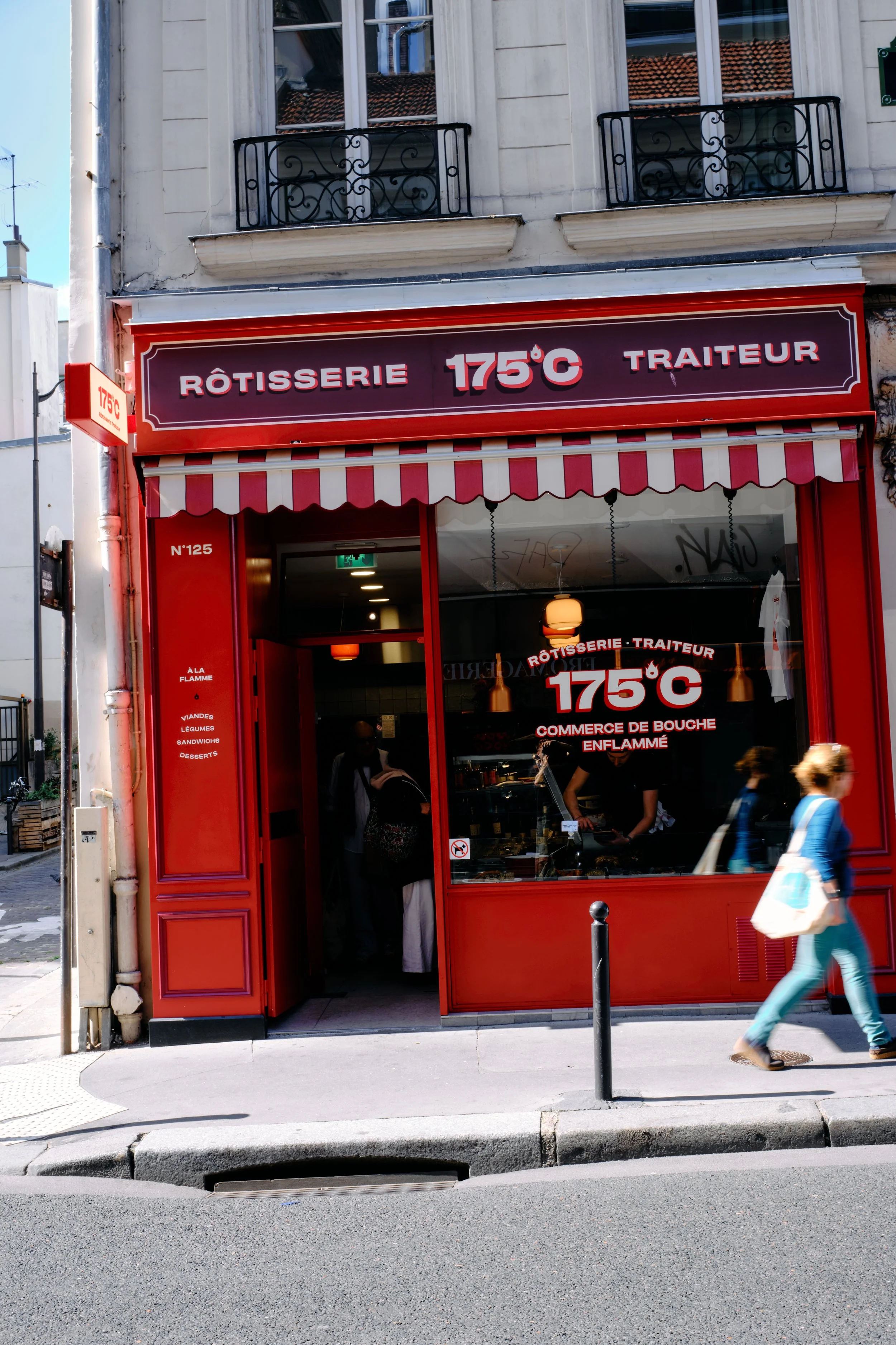 Une façade de boutique rouge avec un panneau indiquant 175°C, spécialisée dans la restauration à emporter ou la cuisine de bouche enflammée, avec quelques personnes passant devant la boutique.