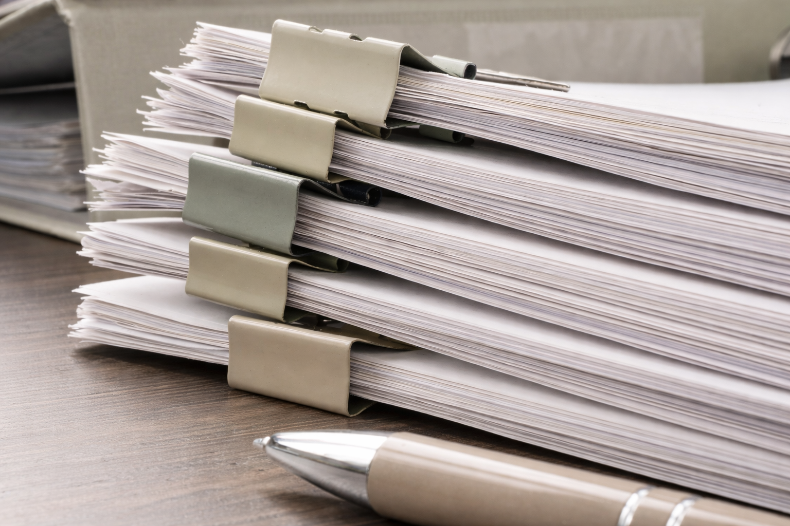 A stack of organized paper documents representing detail‑oriented bookkeeping and QuickBooks work done for local small businesses