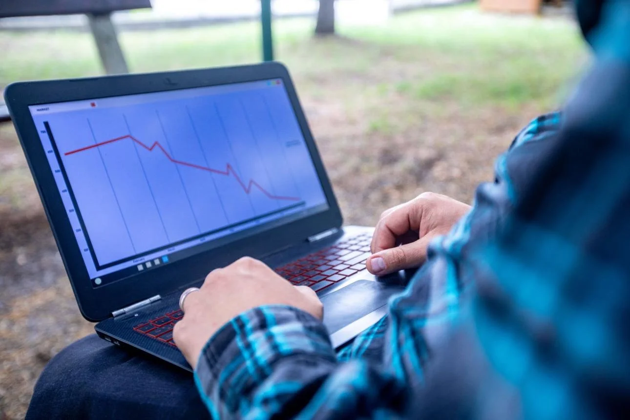 Landscaping business owner reviewing financial reports on laptop showing declining performance and confusion in North Carolina
